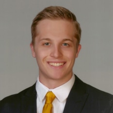 a young man in a suit and tie smiles for the camera