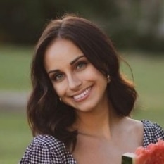 a woman is smiling while holding a piece of watermelon .